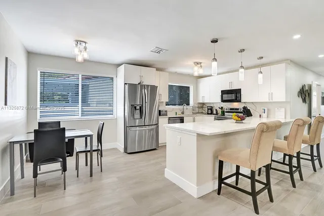 a kitchen with refrigerator a dining table and chairs