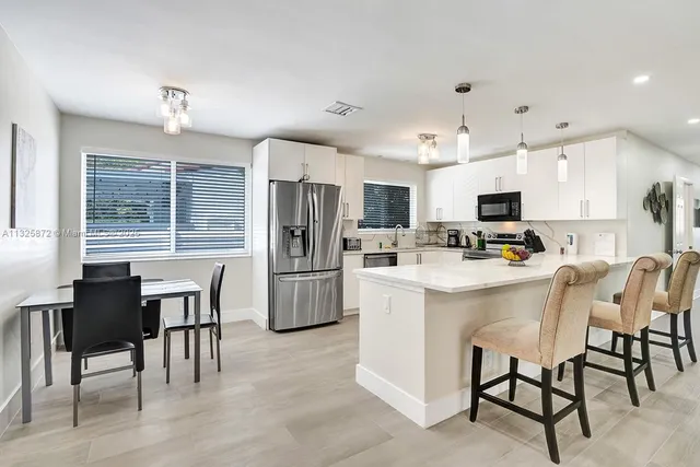 a kitchen with refrigerator a dining table and chairs