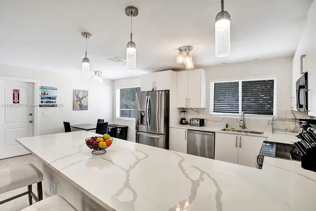 a kitchen with stainless steel appliances kitchen island granite countertop a sink a stove a refrigerator cabinets a dining table and chairs