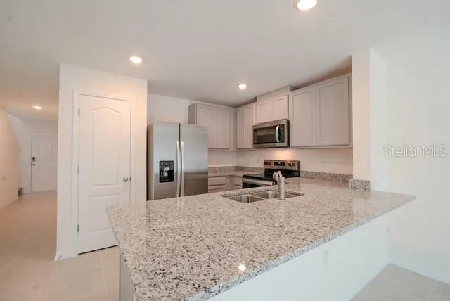 a kitchen with stainless steel appliances granite countertop a sink refrigerator and microwave