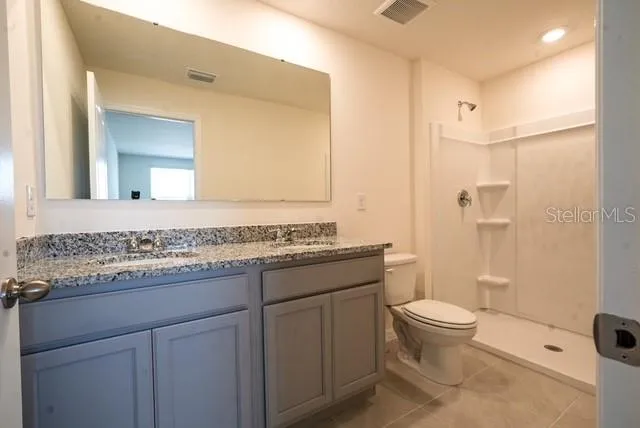 a bathroom with a granite countertop toilet and a sink