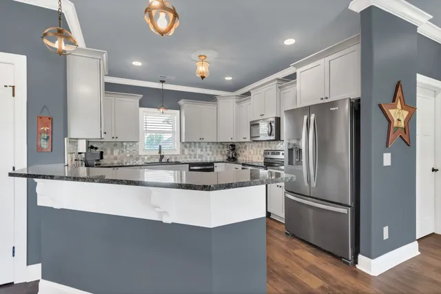 a kitchen with stainless steel appliances granite countertop a refrigerator a stove a sink and a microwave