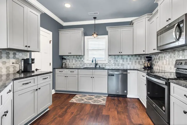 a kitchen with stainless steel appliances granite countertop white cabinets granite counter tops and a hard wood floors
