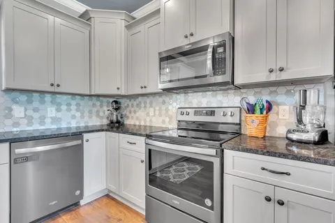 a kitchen with granite countertop white cabinets and stainless steel appliances