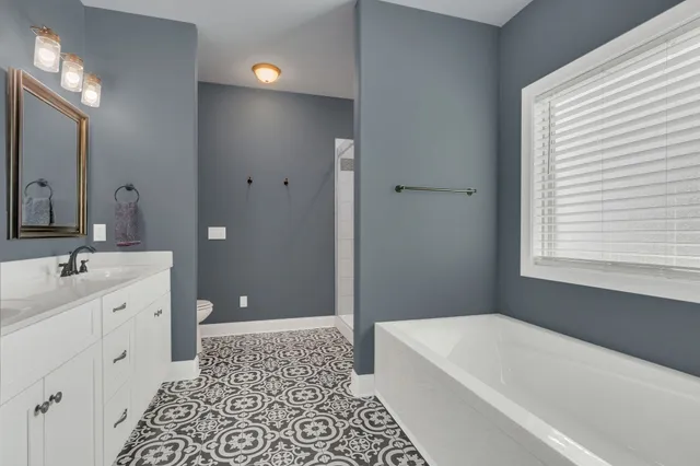 a bathroom with a tub a sink and a large mirror