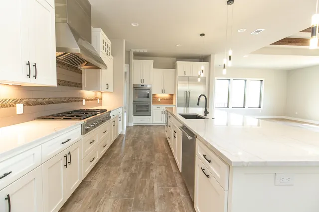 a large kitchen with stainless steel appliances kitchen island granite countertop a large counter top a sink and a stove