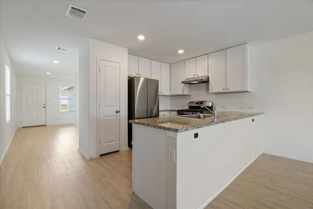 a kitchen with stainless steel appliances granite countertop a refrigerator stove and a sink