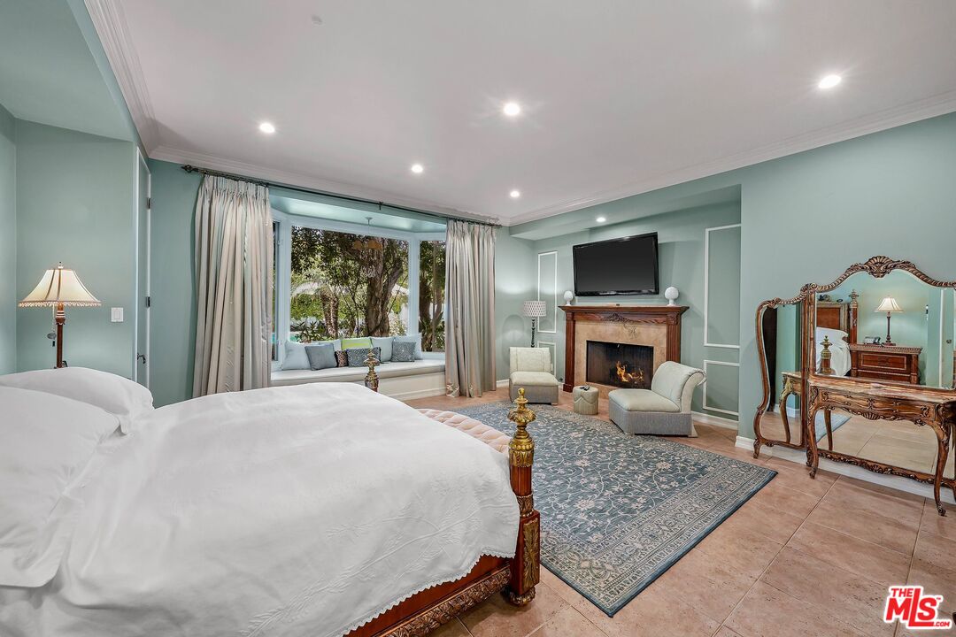 717 North Rodeo Drive Beverly Hills, CA 90210 - Photo 17 of 38 a spacious bedroom with a large bed a fireplace and a couch