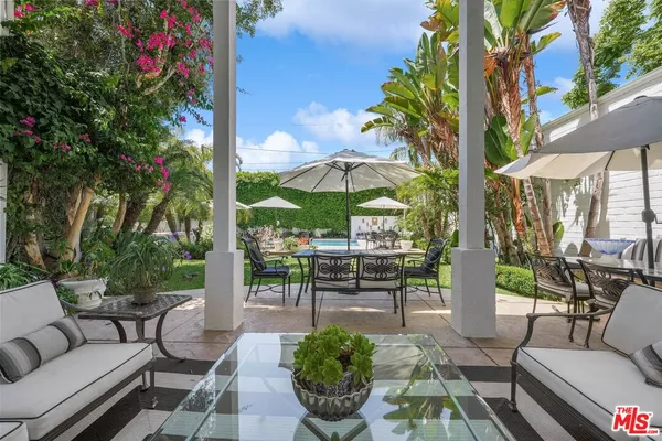 a view of a patio with couches table and chairs under an umbrella with a patio