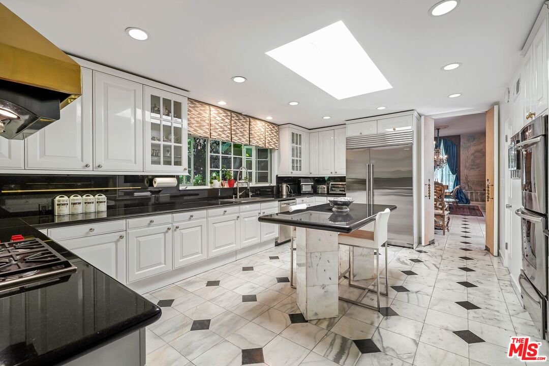 717 North Rodeo Drive Beverly Hills, CA 90210 - Photo 9 of 38 a kitchen with stainless steel appliances kitchen island granite countertop a sink and cabinets