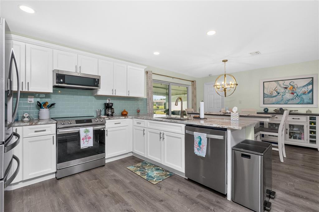 219 Caddy Road Rotonda West, FL 33947 - Photo 16 of 89 a kitchen with stainless steel appliances granite countertop a stove and white cabinets