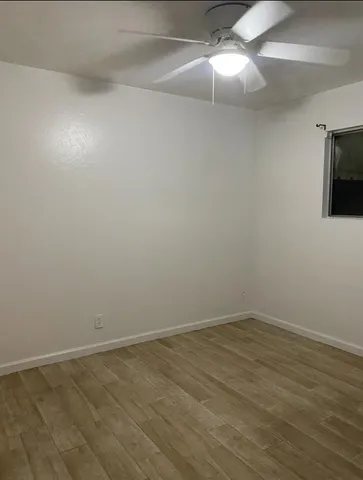 a view of an empty room with wooden floor and windows