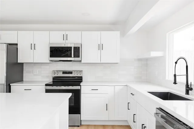 a kitchen with white cabinets stainless steel appliances and sink