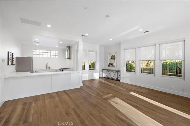 a large white kitchen with lots of counter space wooden floor and windows