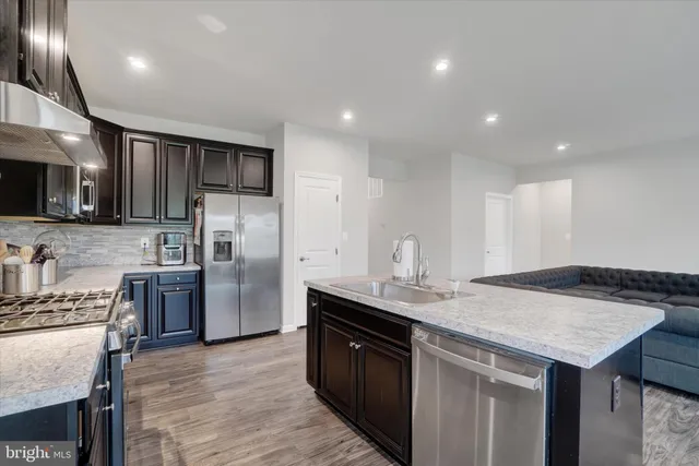 a kitchen with granite countertop kitchen island stainless steel appliances a sink stove and refrigerator