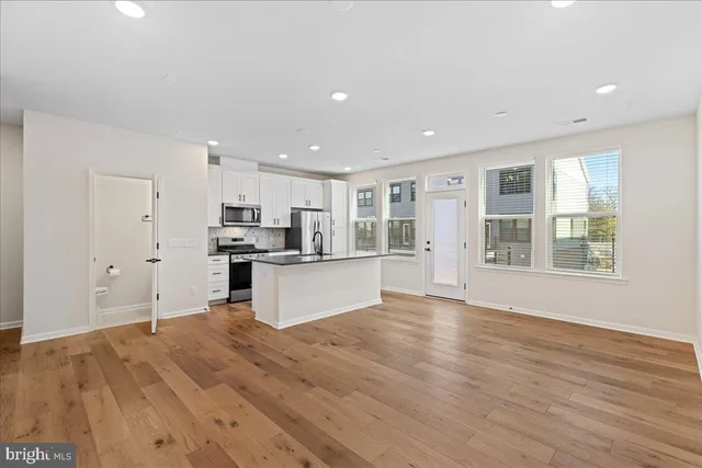 a large kitchen with stainless steel appliances granite countertop a large counter top and a wooden floors