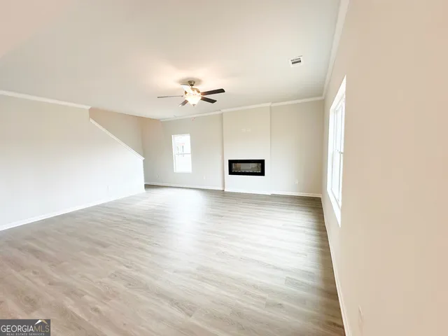a view of empty room with wooden floor and fan