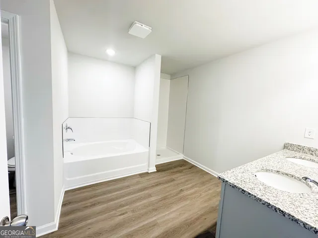 a bathroom with a granite countertop sink and a bathtub