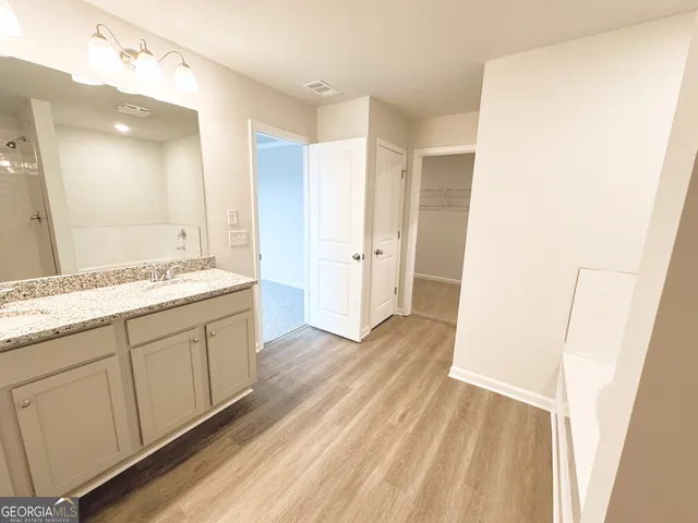 a spacious bathroom with a granite countertop sink a mirror and a shower
