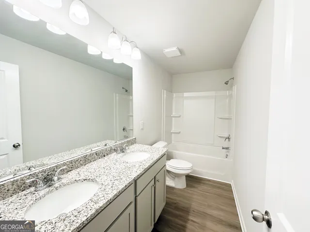 a bathroom with a granite countertop sink a toilet and shower