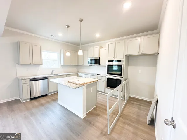 a kitchen with a stove a refrigerator and white cabinets