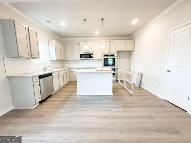 a large white kitchen with wooden floors and white cabinets