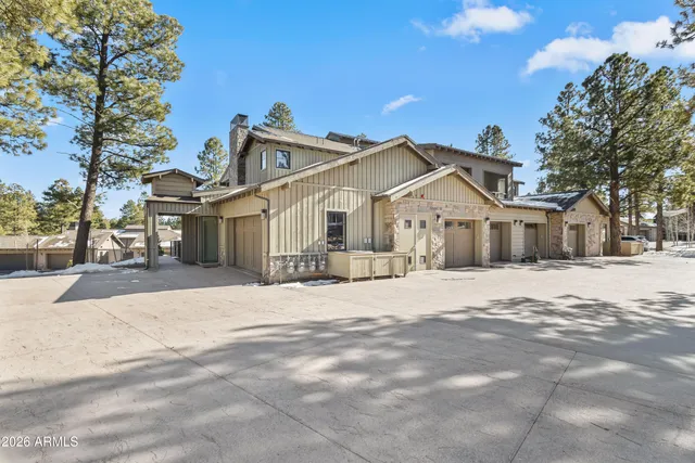 a front view of a house with a dirt yard and a large tree
