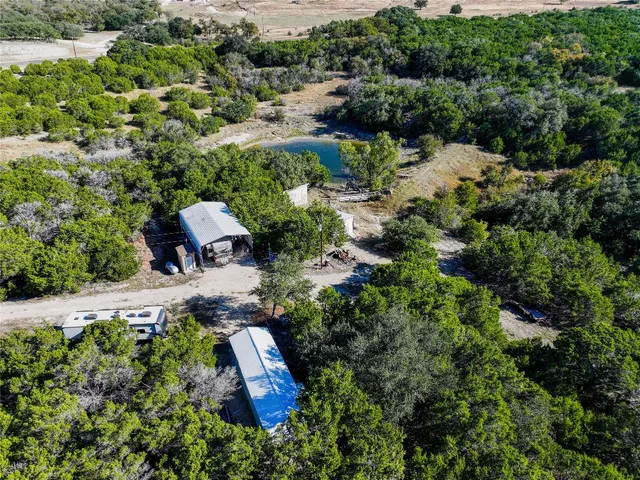 a view of a wooden house with a small yard and large trees