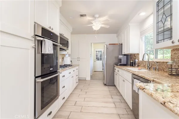 a large kitchen with stainless steel appliances granite countertop a refrigerator and a sink