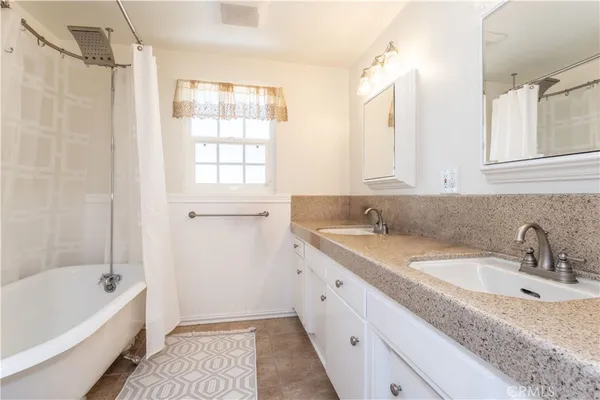 a bathroom with a granite countertop sink a mirror a bathtub and next to a window