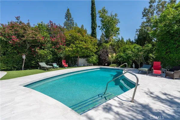 a view of a swimming pool with a patio and a yard