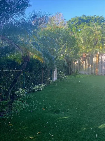 a backyard of a house with plants and large tree