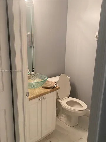 a bathroom with a granite countertop toilet and a sink