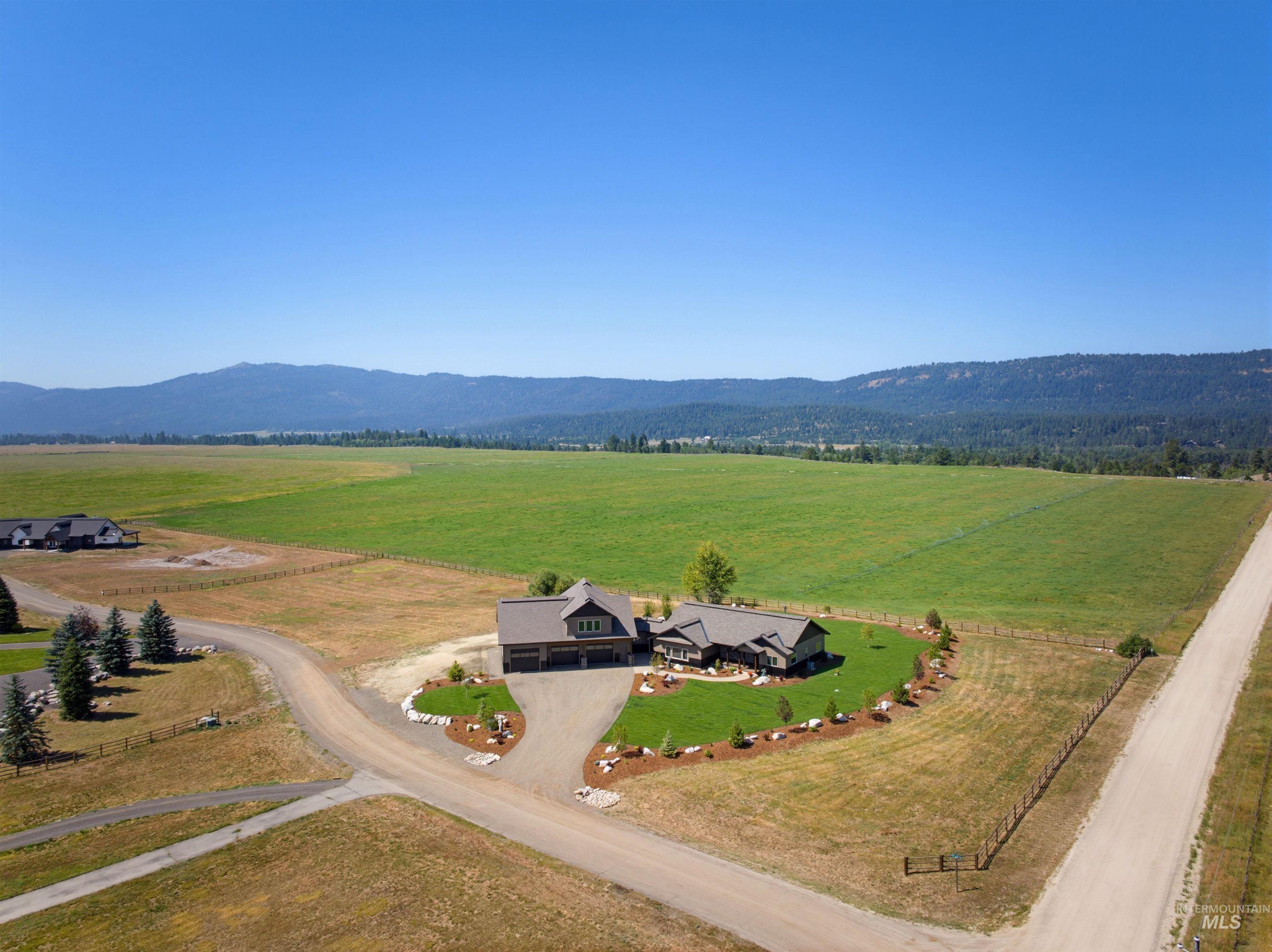 13945 Galloping Road McCall, ID 83638 - Photo 50 of 50 Ranch-style residence featuring a multi-car garage, a gravel driveway, and a manicured lawn with mature landscaping