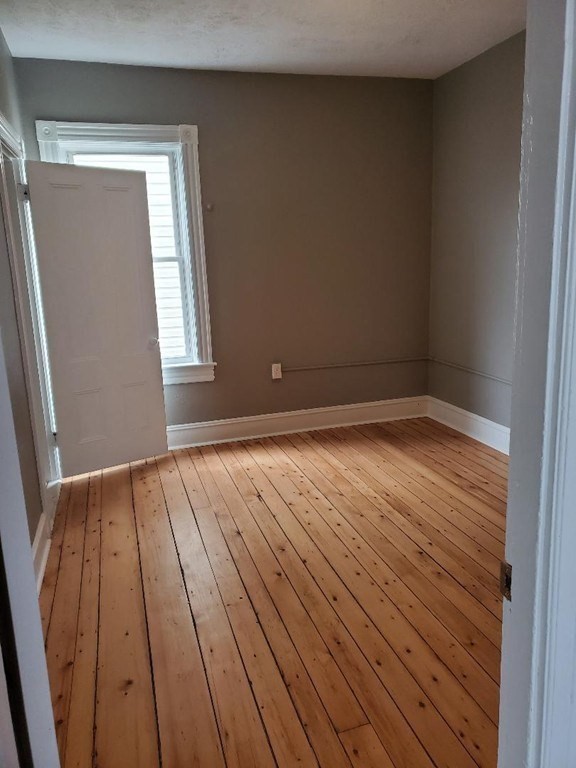 762 Globe Street, Unit 2 Fall River, MA 02724 - Photo 9 of 20 an empty room with wooden floor and windows
