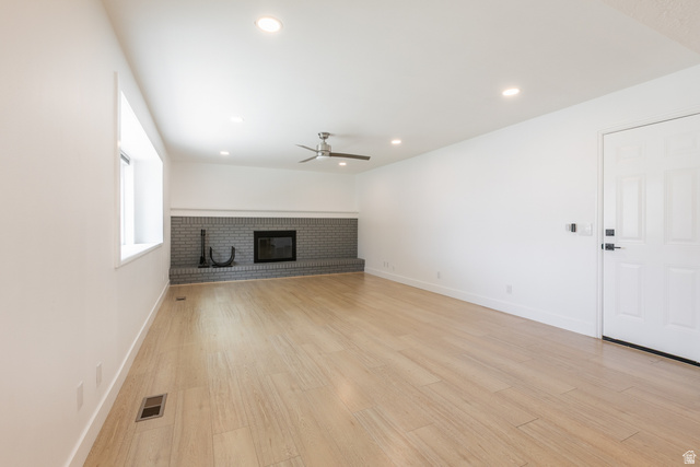 11906 Woodridge Road Sandy, UT 84094 - Photo 12 of 35 Spacious living area featuring light wood-finish flooring, a contemporary fireplace with gray brick surround, a single wide window, and recessed lighting