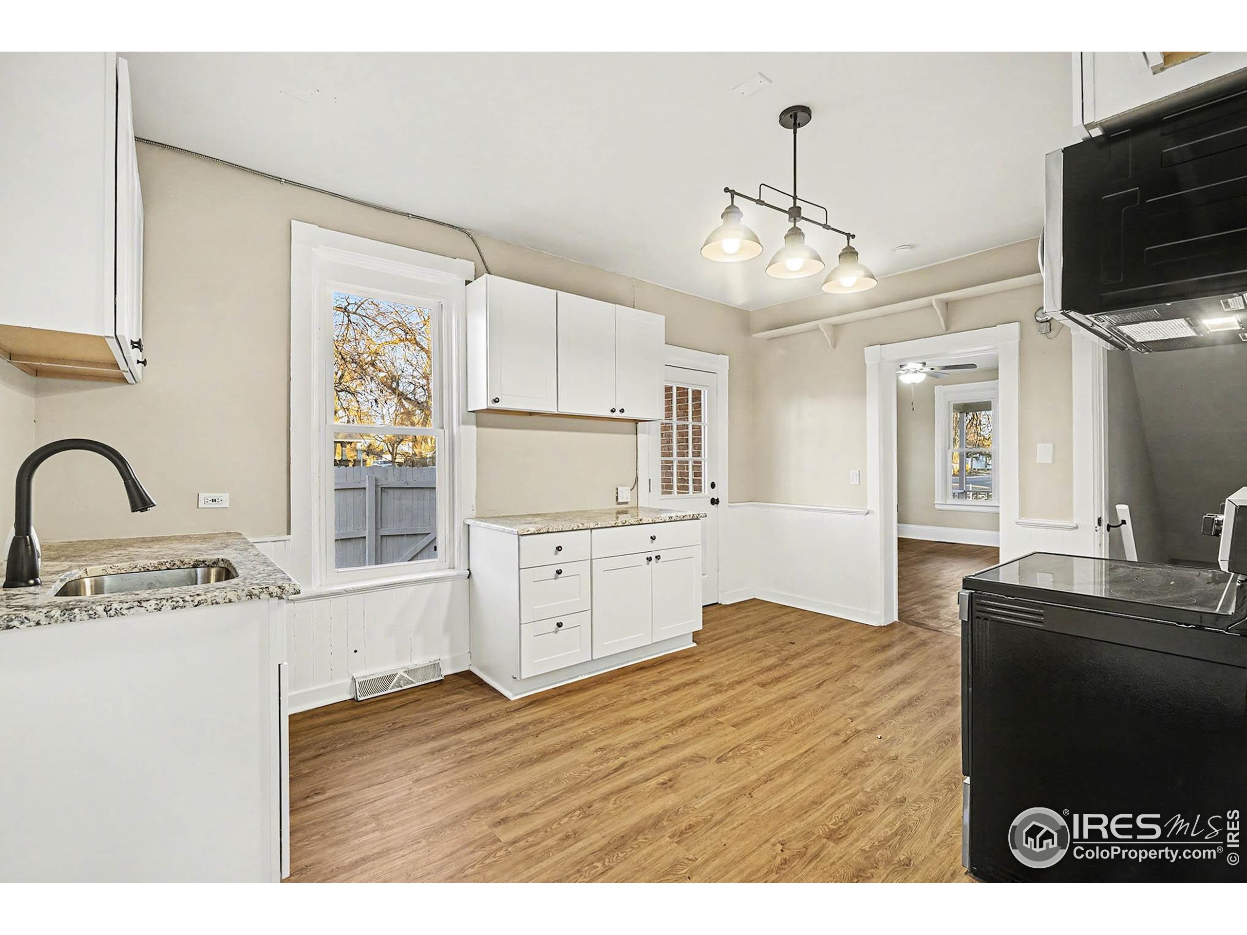 1330 8th Street Greeley, CO 80631 - Photo 13 of 27 a kitchen with granite countertop a stove a sink and a microwave