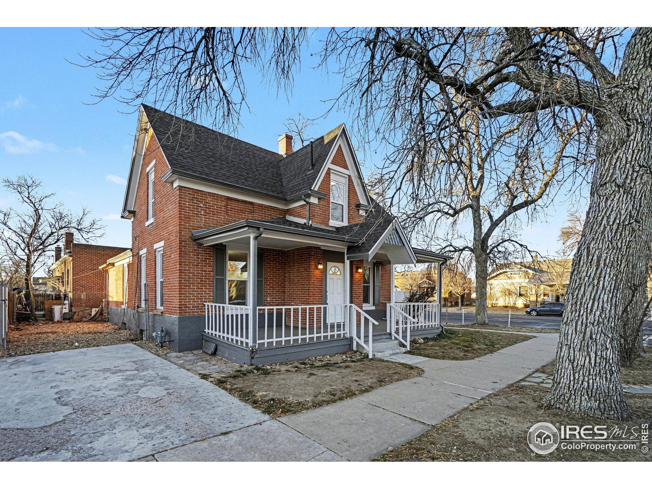 1330 8th Street Greeley, CO 80631 - Photo 4 of 27 a view of a white house with a large tree and wooden fence
