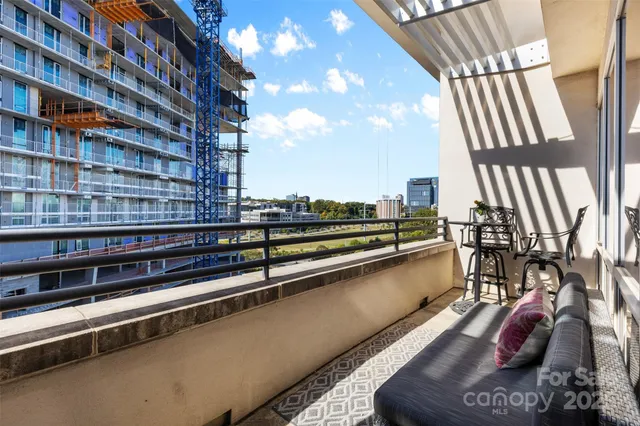 a view of balcony with a couple of cars parked in front of a house