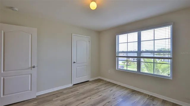 a view of an empty room with wooden floor and windows