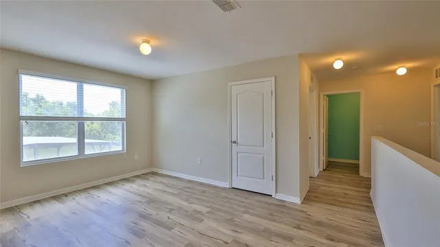 a view of an empty room with closet and wooden floor