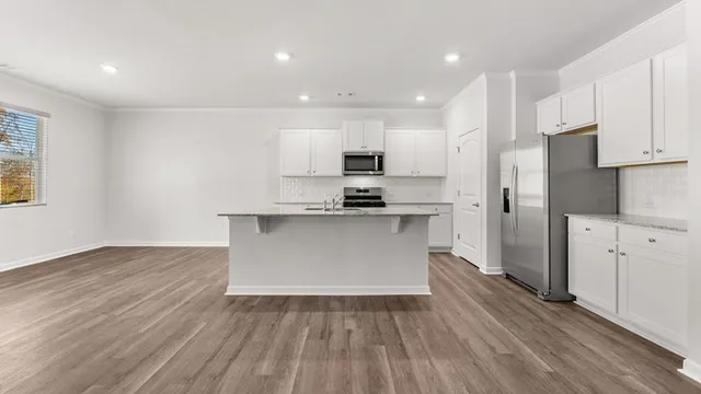 a kitchen with wooden floors white cabinets and stainless steel appliances