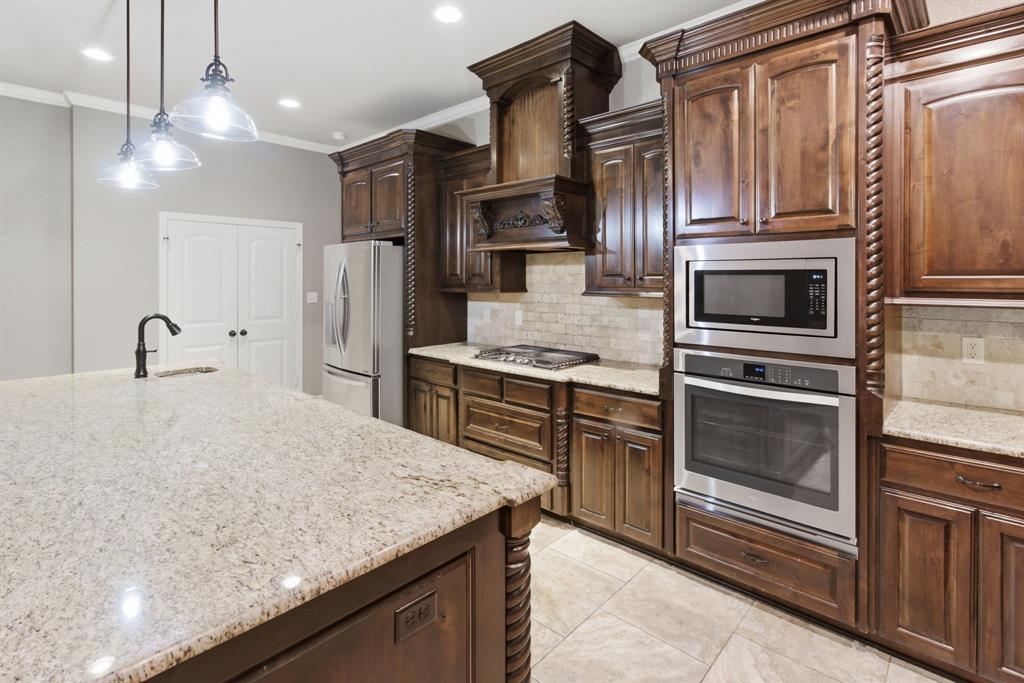 7765 Hickory Spring Lane Tyler, TX 75703 - Photo 20 of 38 Kitchen featuring dark wood cabinetry with decorative rope trim, light granite countertops, stainless steel appliances including a built-in oven and microwave, and a tile backsplash