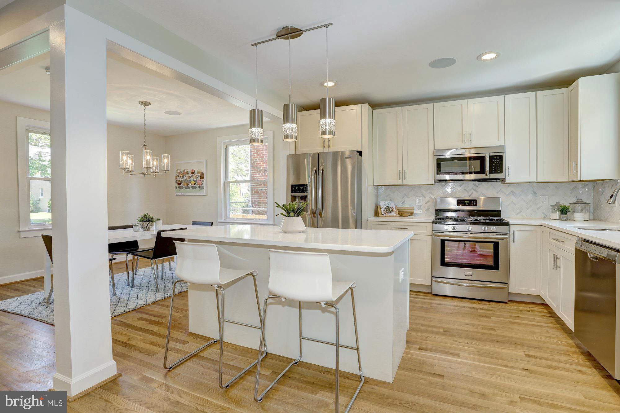 a kitchen with stainless steel appliances a stove a sink dishwasher a refrigerator and white cabinets with wooden floor