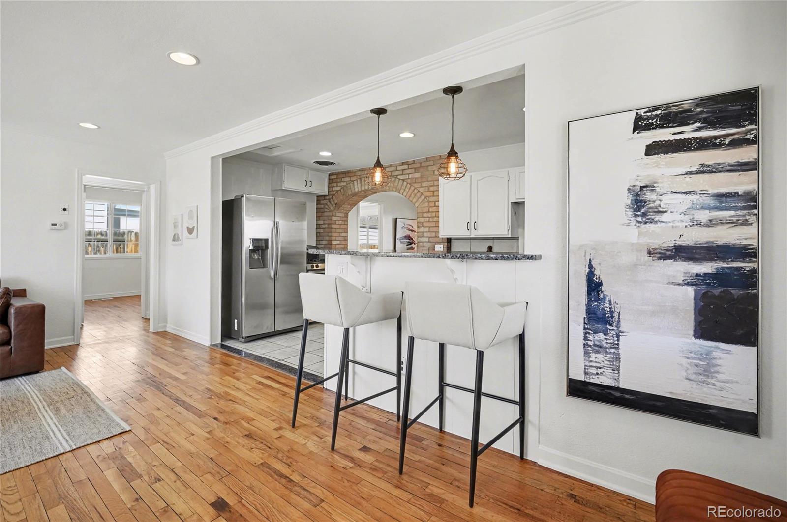 4870 Raritan Street Denver, CO 80221 - Photo 8 of 21 a kitchen with stainless steel appliances kitchen island granite countertop a stove a refrigerator and a dining table with wooden floor