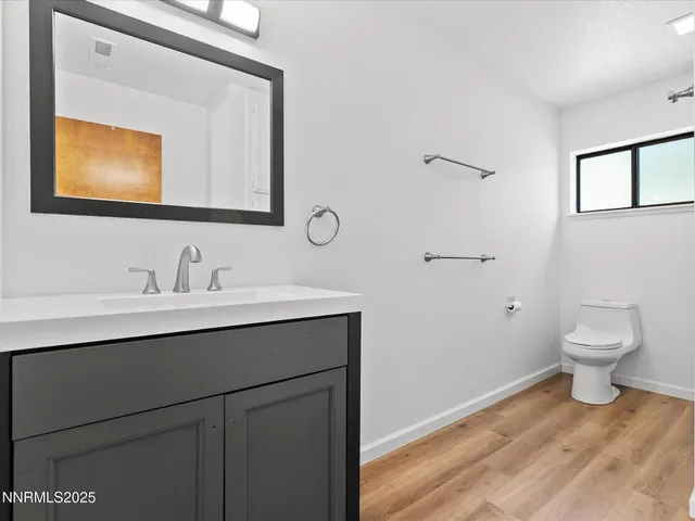 a view of an empty room with wooden floor fireplace and a window