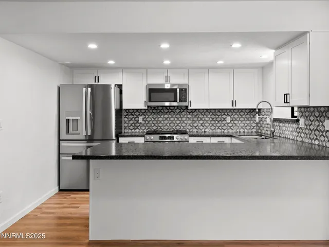 a kitchen with granite countertop white cabinets stainless steel appliances and a sink