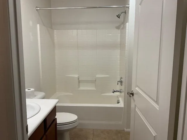 a bathroom with a granite countertop bathtub shower sink vanity and toilet