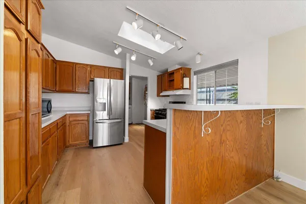 a kitchen with stainless steel appliances granite countertop a refrigerator a stove top oven and a sink