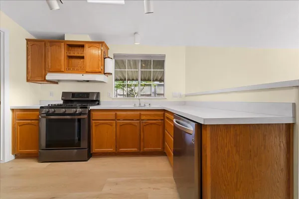 a kitchen with stainless steel appliances granite countertop a stove a sink and a microwave
